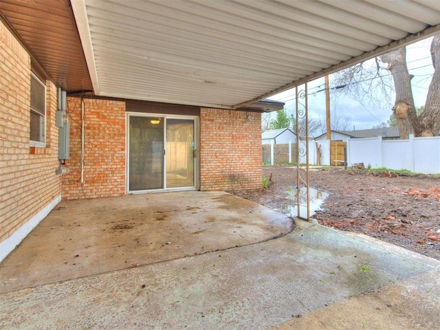 view of patio / terrace featuring a storage shed, a carport, fence, and an outdoor structure