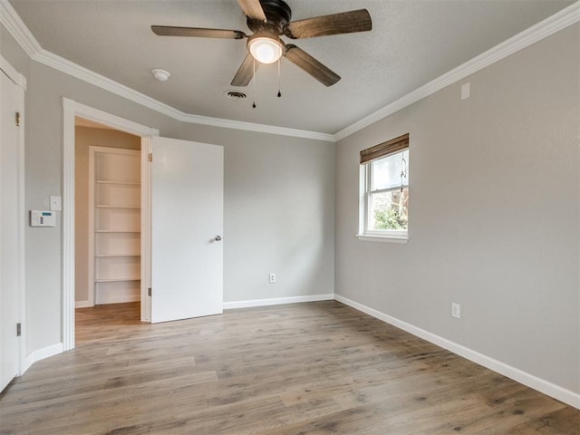 unfurnished bedroom with visible vents, baseboards, ornamental molding, and wood finished floors