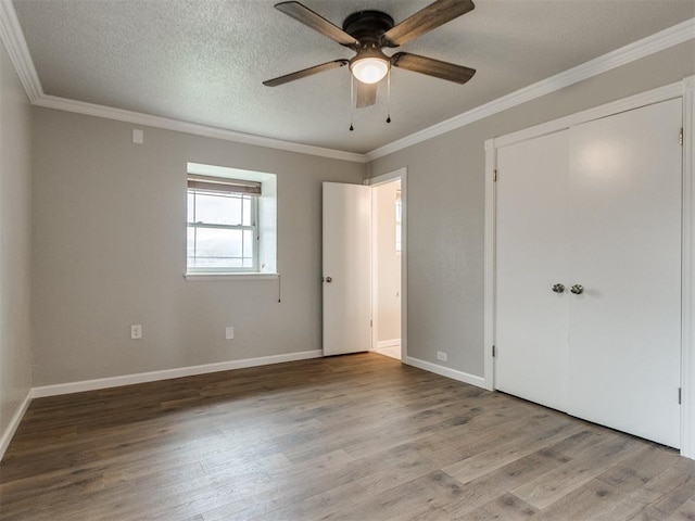 unfurnished bedroom with crown molding, wood finished floors, baseboards, and a textured ceiling