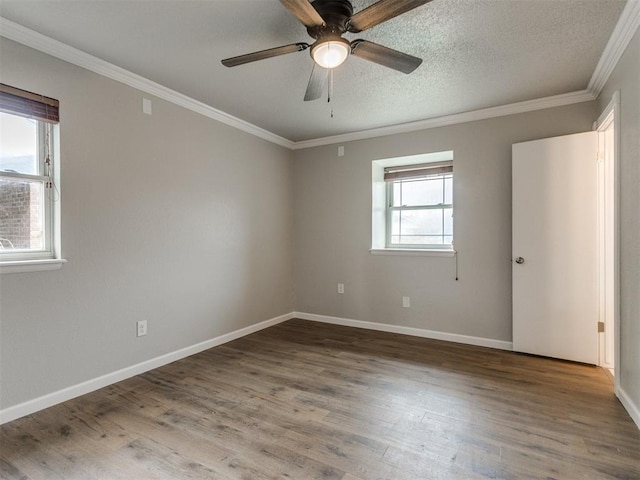 empty room featuring baseboards, a textured ceiling, crown molding, and wood finished floors