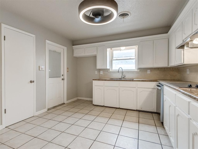 kitchen featuring light tile patterned floors, tasteful backsplash, white cabinetry, a sink, and black electric cooktop