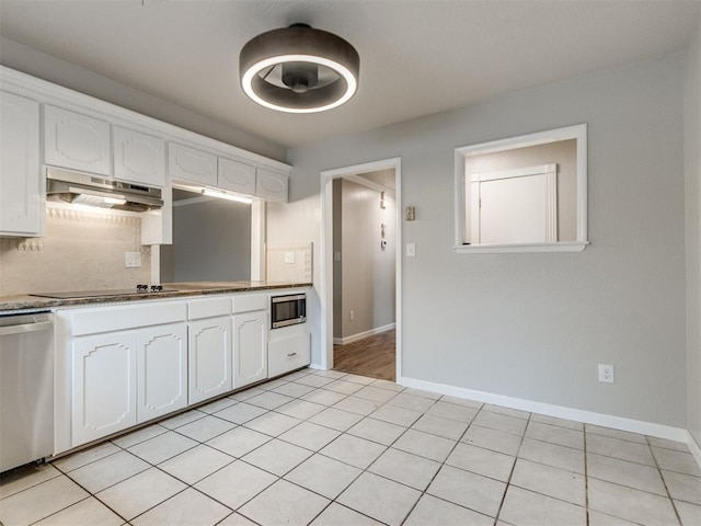 kitchen featuring tasteful backsplash, white cabinetry, appliances with stainless steel finishes, under cabinet range hood, and baseboards