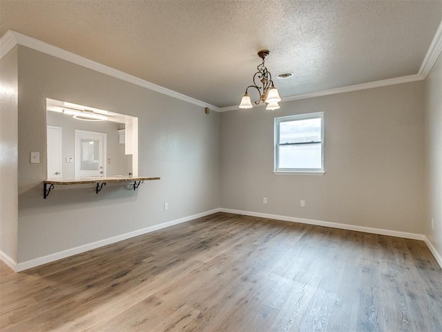 unfurnished room featuring crown molding, baseboards, wood finished floors, and a textured ceiling