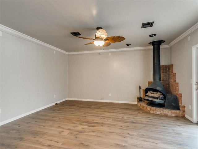 unfurnished living room featuring ornamental molding, visible vents, a wood stove, and wood finished floors