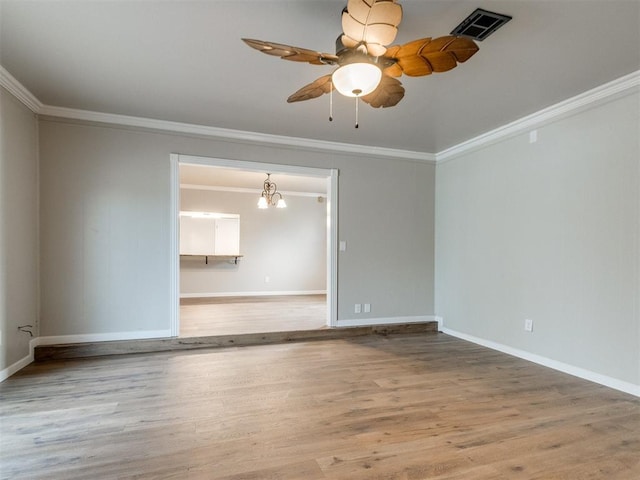 spare room with ornamental molding, visible vents, baseboards, and wood finished floors