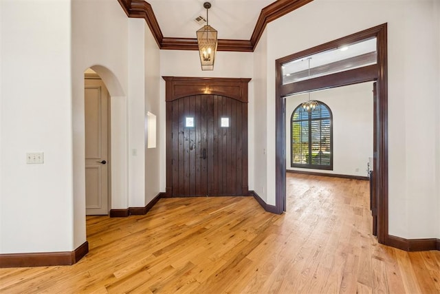 13125 Oakcliff Rd, Oklahoma City, OK 73120 - foyer entrance featuring light wood-type flooring, ornamental molding, a chandelier, visible vents, and arched walkways