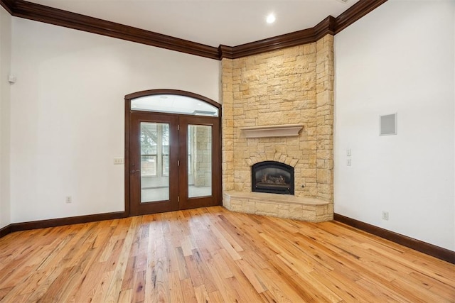 13125 Oakcliff Rd, Oklahoma City, OK 73120 - unfurnished living room featuring baseboards, ornamental molding, a stone fireplace, wood-type flooring, and french doors