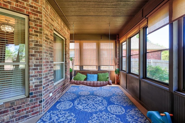 sunroom featuring wooden ceiling and brick wall