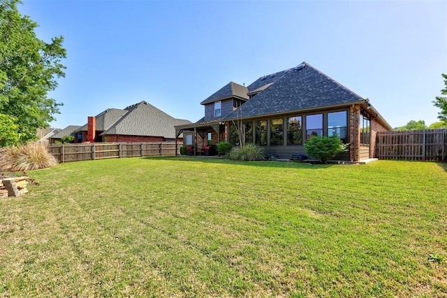 back of house featuring brick siding, a lawn, and a fenced backyard