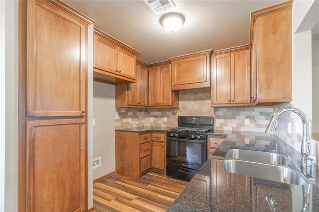 1800 N Nebraska Ave, Oklahoma City, OK 73111 - kitchen with a sink, dark stone counters, gas stove, and light wood-style floors