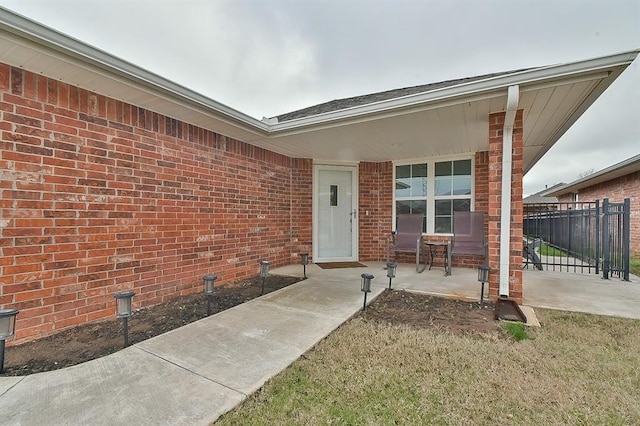 doorway to property with brick siding and fence