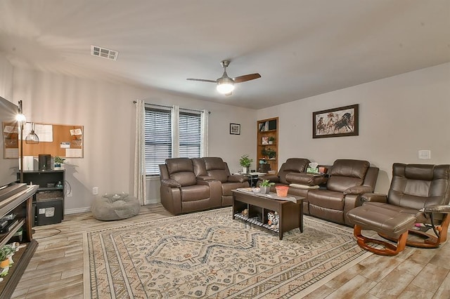living area with visible vents, ceiling fan, light wood finished floors, and baseboards