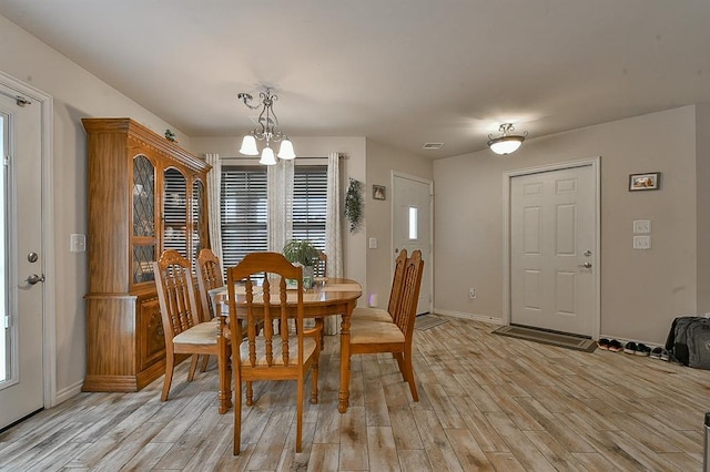dining space featuring baseboards, visible vents, light wood-type flooring, and an inviting chandelier