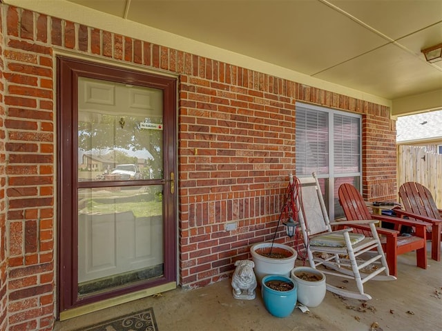view of exterior entry with a porch and brick siding