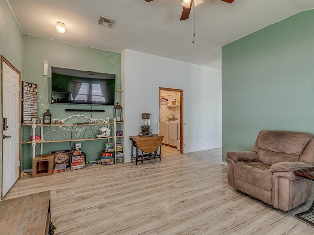 living area with wood finished floors, a ceiling fan, and visible vents