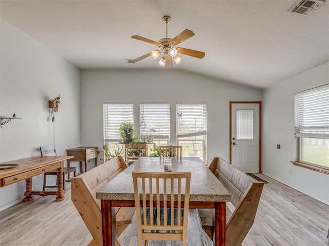 dining room with visible vents, ceiling fan, light wood finished floors, and lofted ceiling