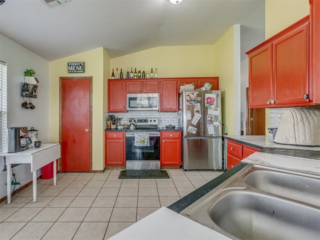 kitchen featuring light tile patterned floors, a sink, lofted ceiling, stainless steel appliances, and backsplash