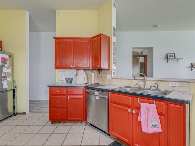 kitchen with a sink, appliances with stainless steel finishes, a peninsula, decorative backsplash, and light tile patterned flooring
