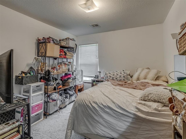 bedroom with a textured ceiling, visible vents, and carpet floors