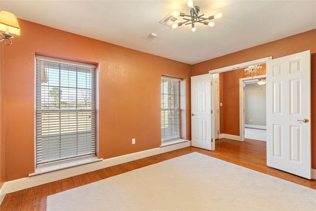 17787 N County Road 3200th Rd, Pauls Valley, OK 73075 - unfurnished bedroom with wood finished floors, an inviting chandelier, and baseboards