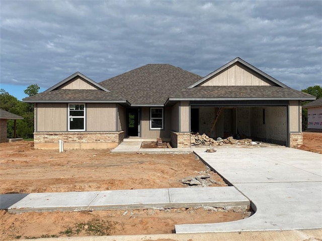view of front of home featuring brick siding, driveway, a shingled roof, and a garage