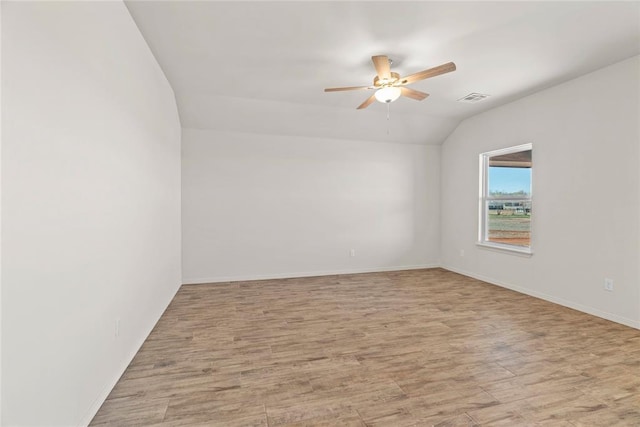 empty room with lofted ceiling, a ceiling fan, visible vents, and light wood-type flooring