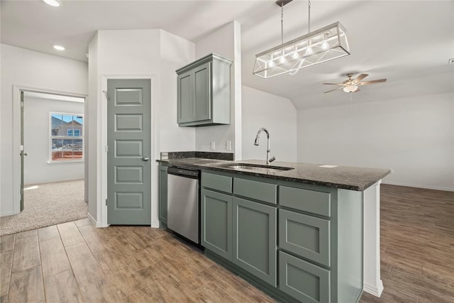 kitchen with dishwasher, wood finished floors, a sink, dark stone counters, and a peninsula