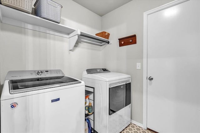 clothes washing area featuring washing machine and dryer, baseboards, light floors, and laundry area