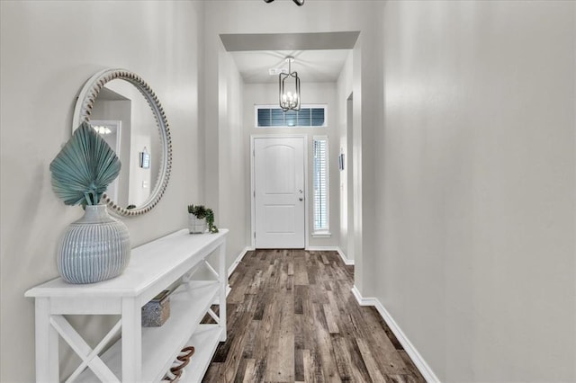 foyer entrance with wood finished floors, visible vents, baseboards, and an inviting chandelier