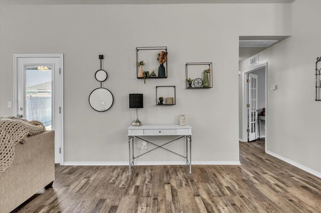 hall featuring baseboards, wood finished floors, and visible vents