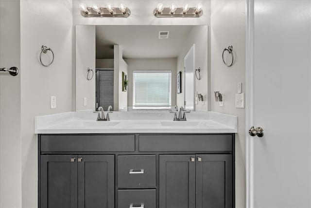 bathroom featuring visible vents, a sink, a shower, and double vanity