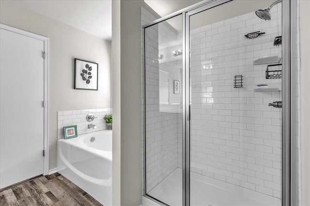 full bath with a bath, a stall shower, and wood finished floors