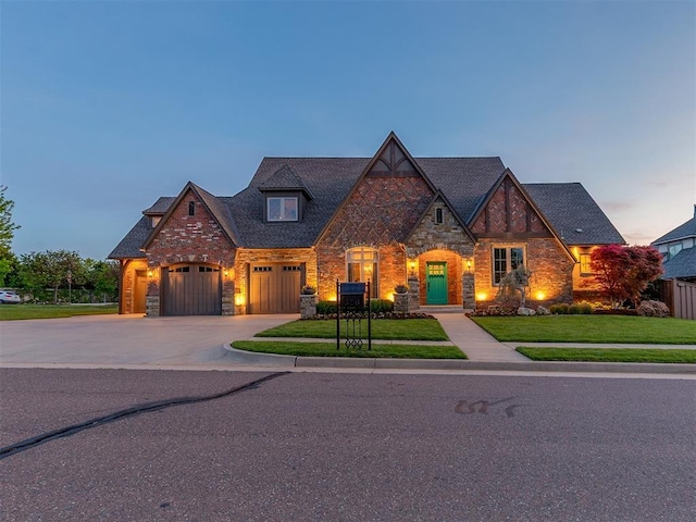 view of front facade with a garage, a front yard, stone siding, brick siding, and concrete driveway