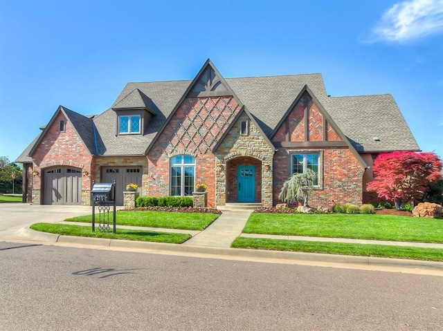view of front of property with an attached garage, a front lawn, roof with shingles, and stone siding
