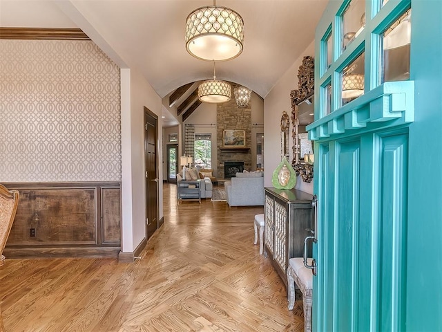 entrance foyer with arched walkways, a fireplace, vaulted ceiling, baseboards, and wallpapered walls