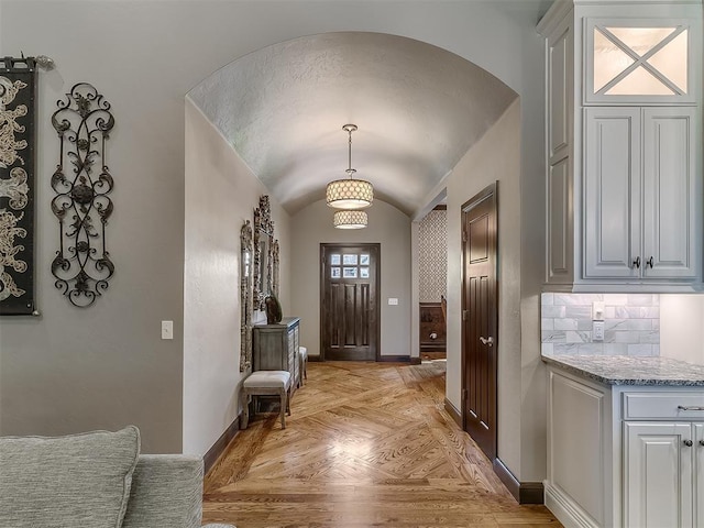 foyer with baseboards, arched walkways, and lofted ceiling