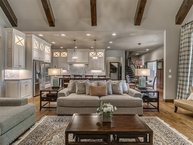 living area with recessed lighting, a barn door, beam ceiling, and stairway