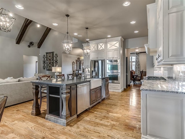 kitchen featuring appliances with stainless steel finishes, a sink, a chandelier, open floor plan, and vaulted ceiling with beams
