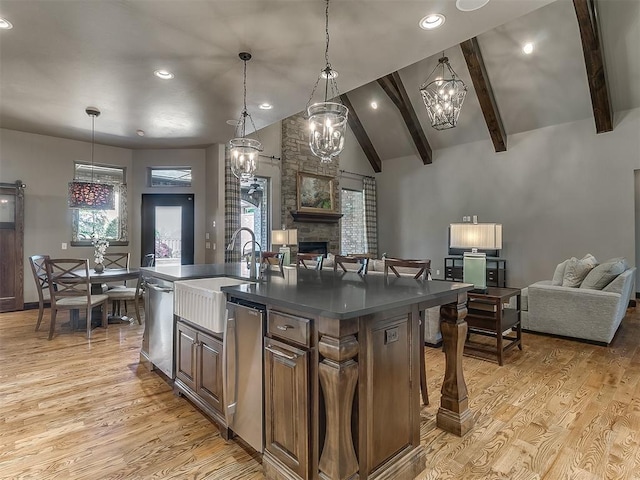 kitchen with dark countertops, a fireplace, light wood-type flooring, lofted ceiling with beams, and open floor plan