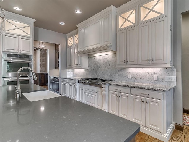 kitchen with white cabinets, appliances with stainless steel finishes, recessed lighting, decorative backsplash, and glass insert cabinets
