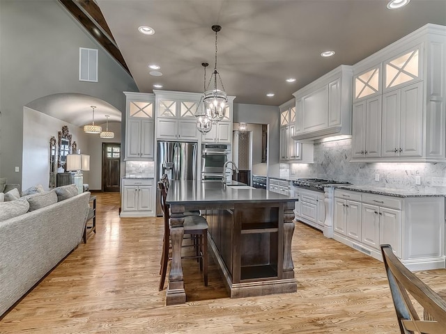 kitchen with appliances with stainless steel finishes, decorative backsplash, lofted ceiling, visible vents, and glass insert cabinets