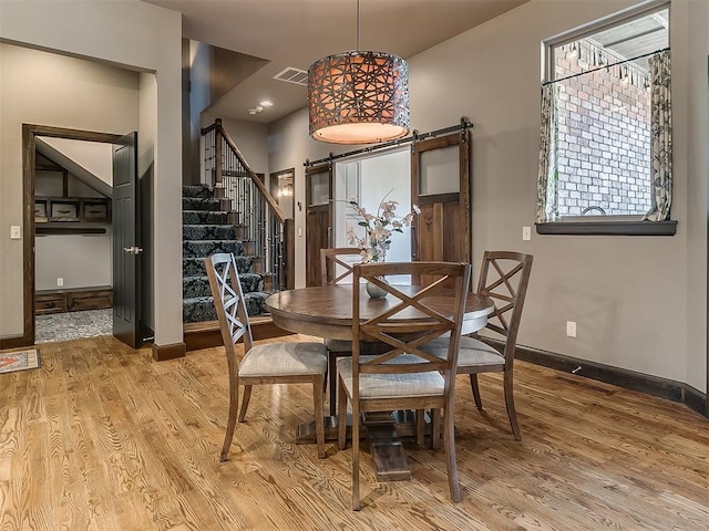 dining space featuring baseboards, light wood-type flooring, stairs, and visible vents