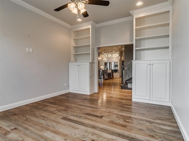 unfurnished living room with ornamental molding, stairs, wood finished floors, baseboards, and a ceiling fan