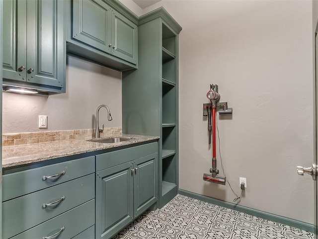 clothes washing area featuring a sink and baseboards