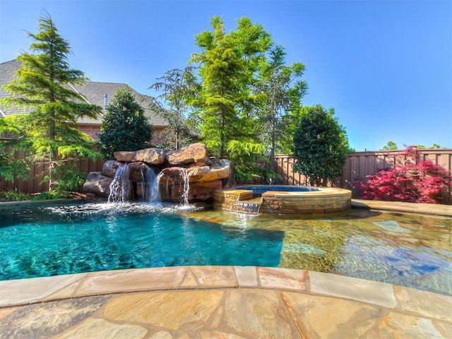 view of swimming pool with a fenced backyard and a pool with connected hot tub