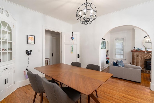 1428 NW 45th St, Oklahoma City, OK 73118 - dining space featuring crown molding, arched walkways, light wood finished floors, baseboards, and a notable chandelier