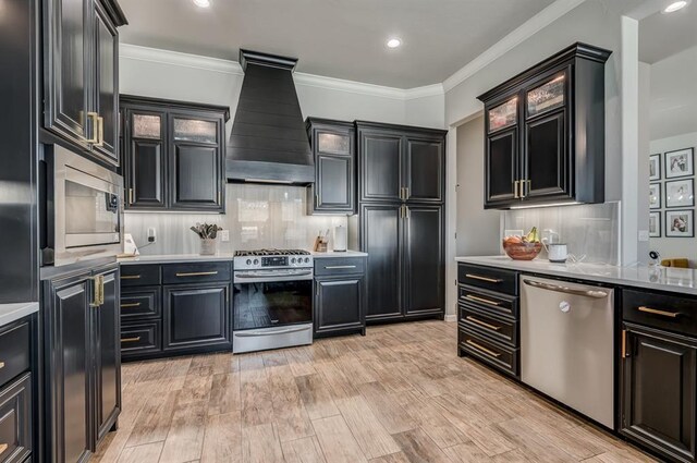 1219 N Adair Ct, Stillwater, OK 74075 - kitchen with custom range hood, light wood-style flooring, light countertops, crown molding, and appliances with stainless steel finishes