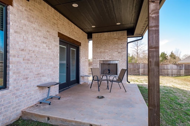 1219 N Adair Ct, Stillwater, OK 74075 - view of patio featuring french doors, fence, and an outdoor brick fireplace