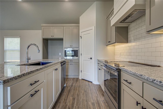4980 12th Ave, Goldsby, OK 73093 - kitchen featuring stainless steel appliances, a sink, wall chimney range hood, light stone counters, and dark wood finished floors