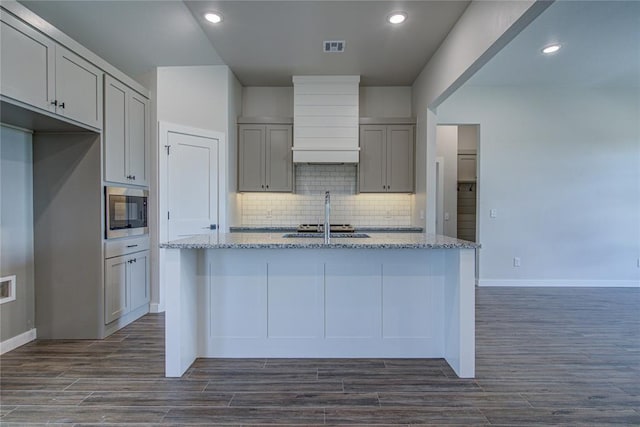 4980 12th Ave, Goldsby, OK 73093 - kitchen with gray cabinets, stainless steel microwave, light stone countertops, premium range hood, and a sink